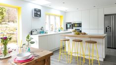 a kitchen with yellow barstools and an island in front of the refrigerator freezer