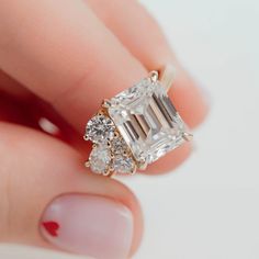 a woman's hand holding an engagement ring with three stones on the side and one stone in the middle