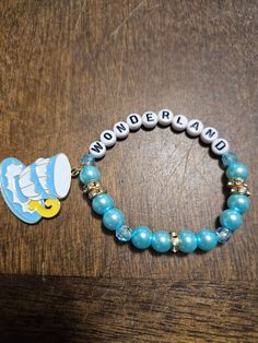 a bracelet with an image of a fish and the word wonderland on it, sitting on top of a wooden table