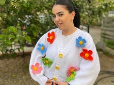 a woman wearing a white sweater with colorful flowers on it