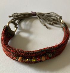 a bracelet with beads and tassels on it sitting on top of a table