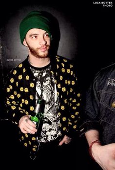 two young men standing next to each other holding beer bottles and looking at the camera