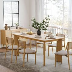 a dining room table with chairs and a vase filled with flowers on top of it