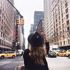 a woman standing in the middle of a city street with her back to the camera