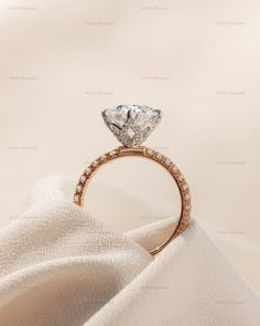 an engagement ring on top of a white cloth with a diamond in the shant