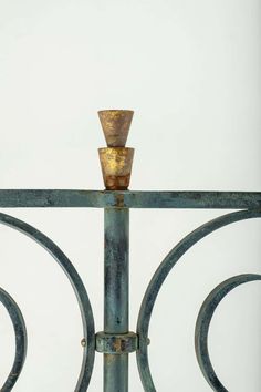 an iron gate with a glass top and metal finial on the bottom, in front of a white wall