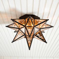 a star light hanging from the ceiling in a room with white walls and wood paneling