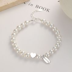 This stunning piece features a delicate strand of lustrous pearls, gracefully encircling your wrist. Nestled in the center, a shimmering silver heart adds a touch of romance, while a finely crafted pendant, engraved with the word "lucky," dangles gracefully, radiating positive energy. Adorn yourself with this timeless treasure, as it embodies the essence of beauty and fortune. Each pearl represents the wisdom gained from life's precious moments, while the silver heart symbolizes love and compass Elegant Adjustable Heart Bracelet For Formal Occasions, Elegant White Gold Heart Bracelet, Elegant Charm Bracelet For Anniversary, Elegant Formal Heart Bracelet With Charm, Elegant Adjustable Heart Charm Bracelet, Elegant Formal Heart Bracelet With Heart Charm, Elegant Sterling Silver Jewelry With Heart Beads, Elegant White Gold Charm Bracelet For Valentine's Day, Elegant Heart Shaped Beaded Jewelry