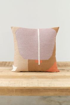 a pillow on top of a wooden table with a white wall in the back ground