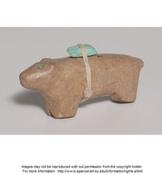 a small ceramic animal with a green bow on its head