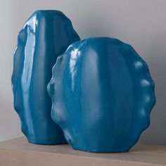 two large blue vases sitting on top of a wooden shelf next to each other