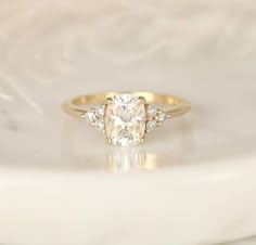 an oval diamond ring with three smaller diamonds on it's side, sitting on a white marble surface