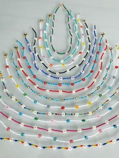 multicolored beaded necklaces are arranged on a white surface with beads in the shape of a triangle