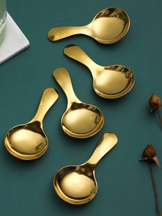 four gold spoons sitting on top of a green table