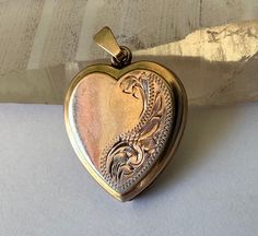 "a sweet gold locket, not tiny, with victorian style engraving and places for photos.  it's marked 9ct bk and ft, which i believe means the faces are gold but the inside is not.  it has the little heart inserts that hold the photos are there, although they have some kinks from being moved in and out, also the little plastic windows are there.  heart has a few tiny dents and some very light scratching but basically looking good.  closes well. toatl height:  a bit under 1 and 1/8\" height of heart Vintage Double Heart Engraved Locket Necklace, Heirloom Engraved Locket Necklace For Valentine's Day, Victorian Locket Necklace For Valentine's Day, Antique Heart-shaped Locket Necklace With Vintage Charm, Antique Heart Locket Necklace With Vintage Charm, Antique Gold Heart Charm Locket Necklace, Victorian Engraved Rose Gold Locket Necklace, Victorian Heart Pendant Locket Necklace For Anniversary, Antique Heart Charm Locket Necklace For Anniversary