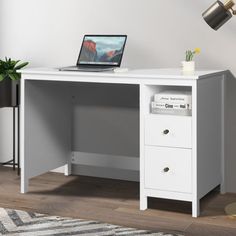 a white desk with a laptop on it and a plant in the corner next to it