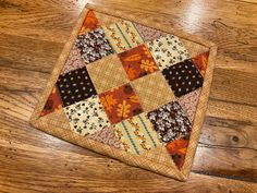 an orange and brown patchwork square on a wooden floor