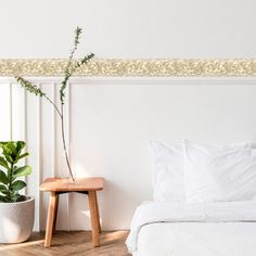 a white bed sitting next to a plant on top of a wooden table