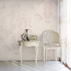 two white chairs sitting next to each other in front of a wallpapered room