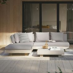 a couch sitting on top of a wooden floor next to a glass wall covered in windows