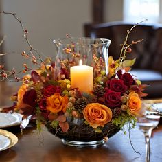 a centerpiece with flowers and candles on a table in front of a brown chair