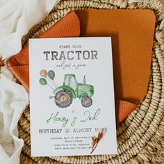 a tractor birthday party card on top of a basket with orange napkins and an orange envelope