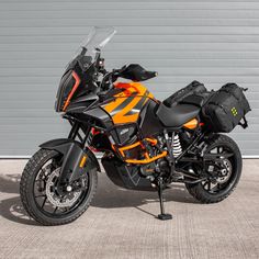 an orange and black motorcycle parked in front of a garage door