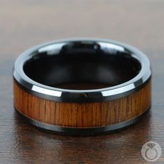 a wooden ring with black ceramic inlays sits on a table, ready to be worn