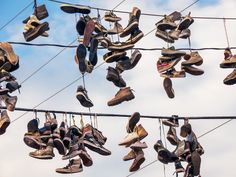 many pairs of shoes are hanging on the power lines with sky in the back ground