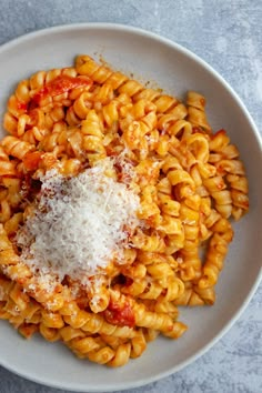 a white plate topped with pasta covered in sauce and parmesan cheese