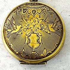 an antique gold pocket watch with ornate designs on the front and sides, sitting on a white surface