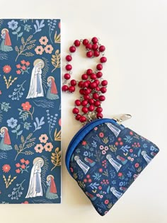 "Rosary Pouch with pattern of Our Lady of Lourdes and Bernadette Size: 3.75\" x 3.25\" Material : Neoprene  All other items on the picture are not included in the purchase. They are elements to show the dimensions of the pouch." Blue Zipper Coin Purse As Gift, Rosary Pouch, Personalized Rosary, Our Lady Of Lourdes, Lady Of Lourdes, Confirmation Gifts, Catholic Gifts, Catholic Art, Lego Friends