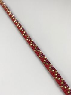 a red and gold bracelet on a white surface