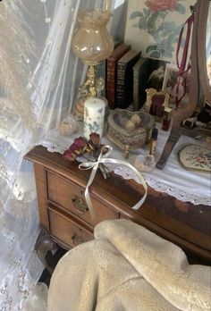 an old dresser is covered with lace and other antique items, including a candle holder