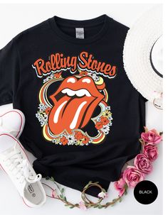 Step back in time and rock out in style with our Vintage Flower Rolling Stone Tee! 🌸🎸 This retro-inspired t-shirt features a classic Rolling Stone logo beautifully intertwined with vibrant flowers, capturing the free-spirited essence of rock 'n' roll and the timeless charm of the 70s. 🌼✨ Crafted from super-soft, high-quality fabric, this tee offers ultimate comfort and a perfect fit, making it an essential addition to your wardrobe. Whether you're heading to a concert, a festival, or just channeling your inner rock star, this tee will have you looking effortlessly cool and totally groovy. 🌟👕 Get ready to roll and bloom with style! 🌿🎶🛒 Retro Graphic Print T-shirt For Spring, Black Hippie Top With Letter Print, Black Top With Vintage Print For Summer, Black Vintage Print Top For Summer, Black Retro T-shirt With Vintage Print, Retro Letter Print Tops For Festival, Spring Hippie Retro Print T-shirt, Vintage Spring Top For Concerts, Summer Band Merch Printed T-shirt