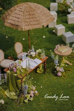 a table with an umbrella and flowers on it in the middle of some grass area