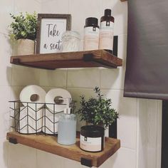 two wooden shelves holding toilet paper, candles and other personal care items in a bathroom