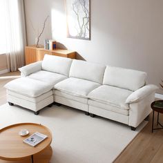 a living room with a white sectional couch and coffee table in the corner, along with a painting on the wall