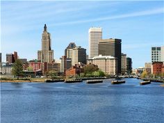 the city is surrounded by tall buildings on either side of the river, and there are boats in the water