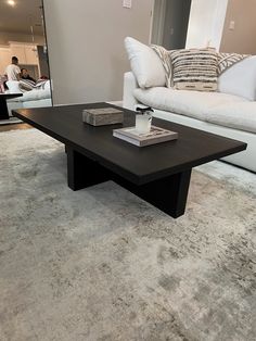 a black coffee table sitting on top of a carpeted floor next to a white couch