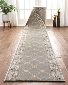 a long gray rug on the floor in front of a window with potted plants