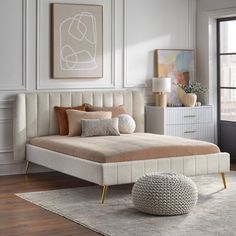 a white bed sitting next to a window on top of a wooden floor in a bedroom