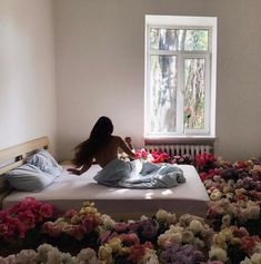 a woman laying on top of a bed in a room with flowers all over the floor