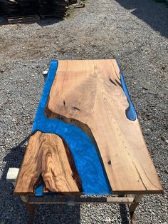 a piece of wood with blue paint on it sitting in the middle of some gravel