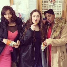 three women standing next to each other holding something in their hands