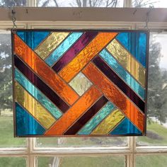 a stained glass window with an orange, blue and yellow pattern hanging from it's side