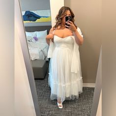 a woman in a white dress taking a selfie