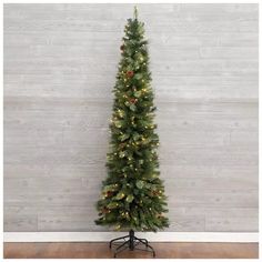 a small christmas tree with lights on it in front of a wooden wall and floor