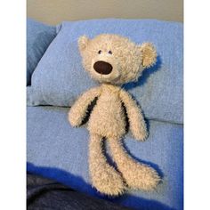 a teddy bear sitting on top of a blue pillow