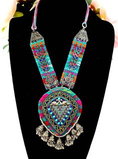 Vibrant, colorful, energetic Afghani Kuchi pendant necklace, that will go with any outfit!   It says "Look at me".  You will be noticed wearing this dramatic necklace! Colorful stiffened fabric pendant and sides, embellished with layers of textures, colors and shapes - eye-catching beads, glowing colored glass, detailed silver tone peacock and flower motif.  A row of delicate jhumka bells are suspended from the bottom. On comfortable velvet backing, to ensure a comfortable fit for you.  Adjustable length via sliding silvertone bead on cotton threads, from 7 in to 12 in.  Pendant 5"H x 3 3/4"W   The jhumka are half jhumka, made so that the jhumka lie flat and don't flip up, complimentary to the design.   Shop more necklaces here: https://www.etsy.com/shop/BoutiqueByMaryam?section_id=2169465 Handmade Necklaces For Festivals, Festive Multicolor Beaded Necklace With Latkans, Bohemian Turquoise Beaded Necklaces For Festive Occasions, Handmade Festival Necklaces, Bohemian Style Turquoise Beaded Necklace For Festive Occasions, Handmade Traditional Bib Necklaces For Festivals, Bohemian Handmade Pendant Bib Necklace, Bohemian Multicolor Beaded Necklace With Boho Collar, Multicolor Bohemian Beaded Necklace With Boho Collar